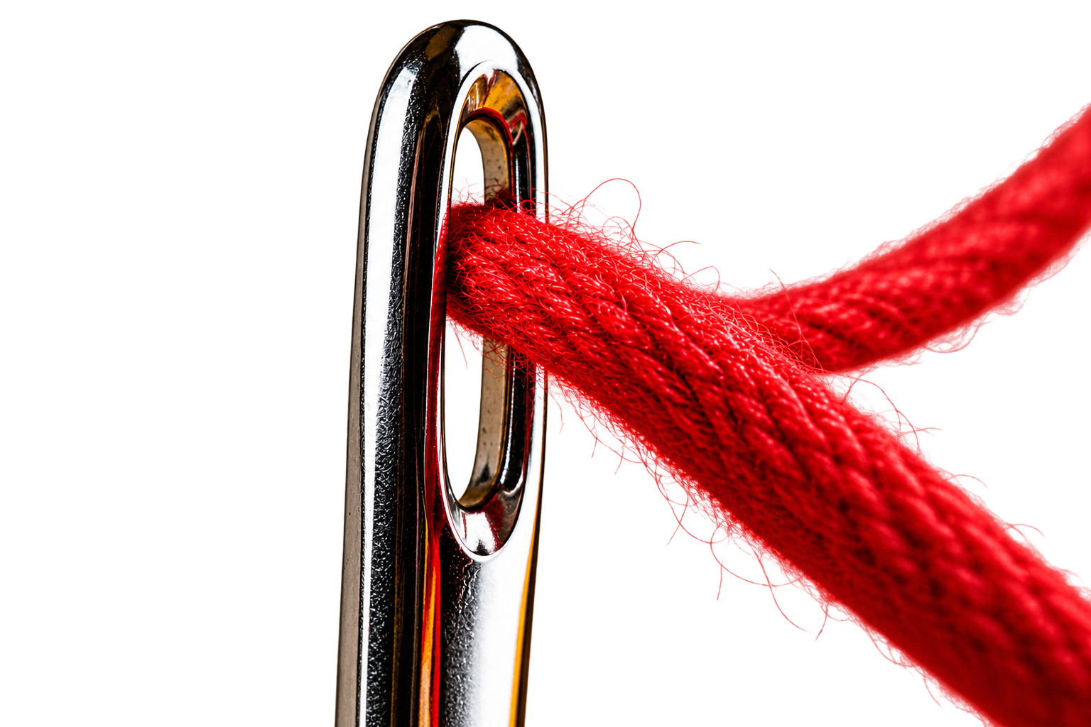 Close-up of a sewing needle with red thread already through the eye.